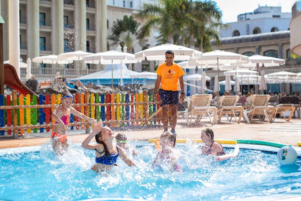 Betreuer spielt mit Kindern im Swimmingpool des Hotels Bahía Princess