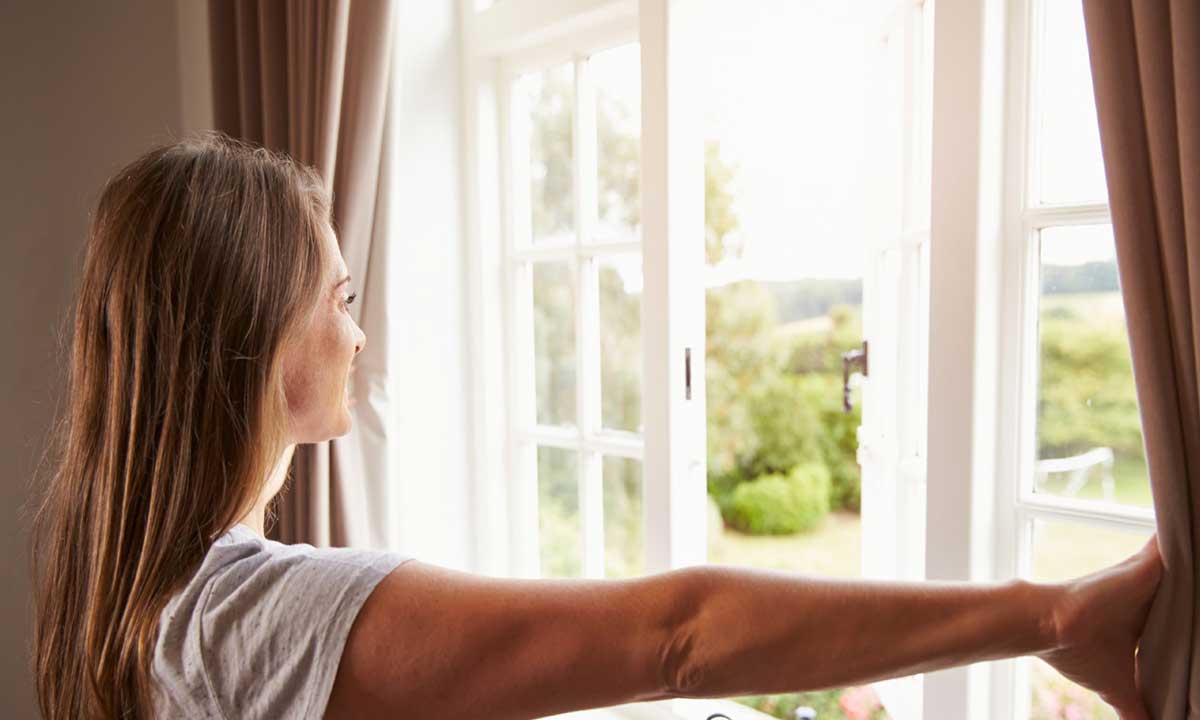 Junge Frau öffnet ein Fenster, um schlechte Energie zu vertreiben