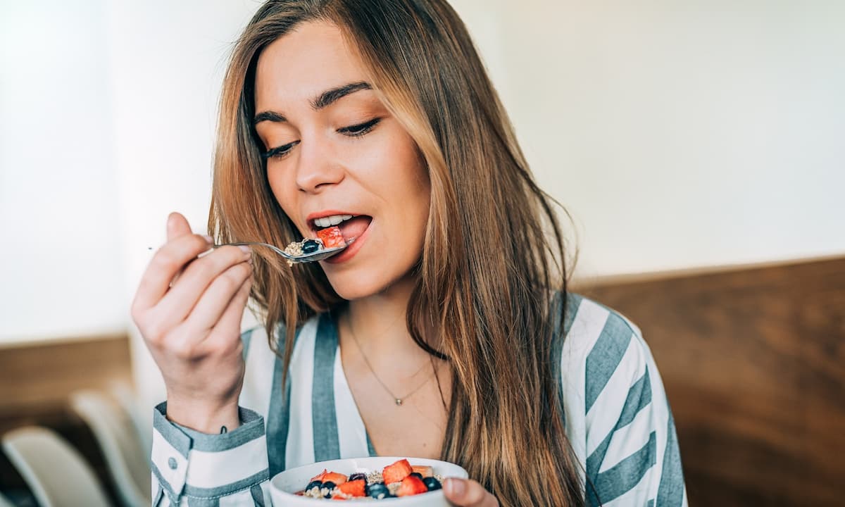 Junge Frau isst eine Schale voller Beeren