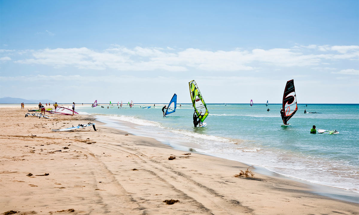 Playa de arena dorada con tablas de windsurf