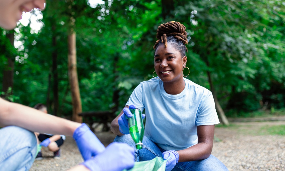 Mujer reciclando vidrio en la naturaleza