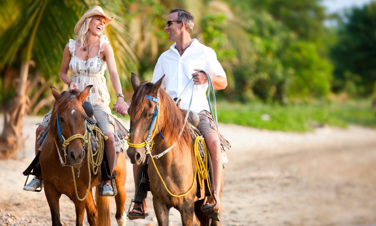 A couple horseback riding on the beach