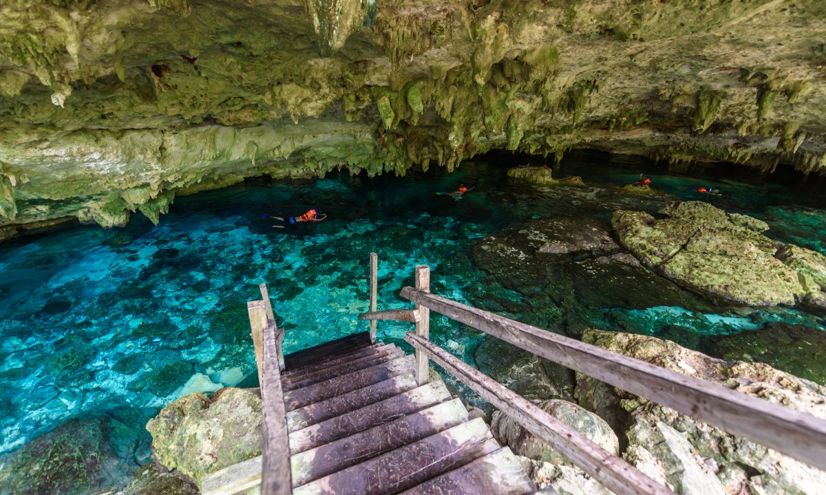 Steps down to a cenote with people diving