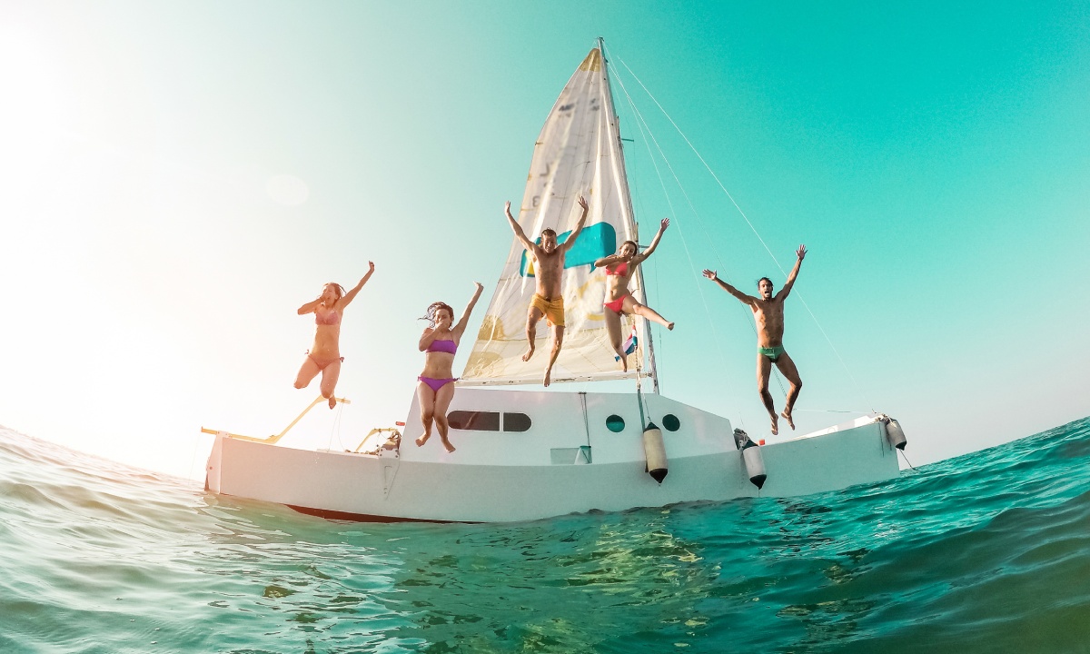 A group of friends jumping off a sailboat