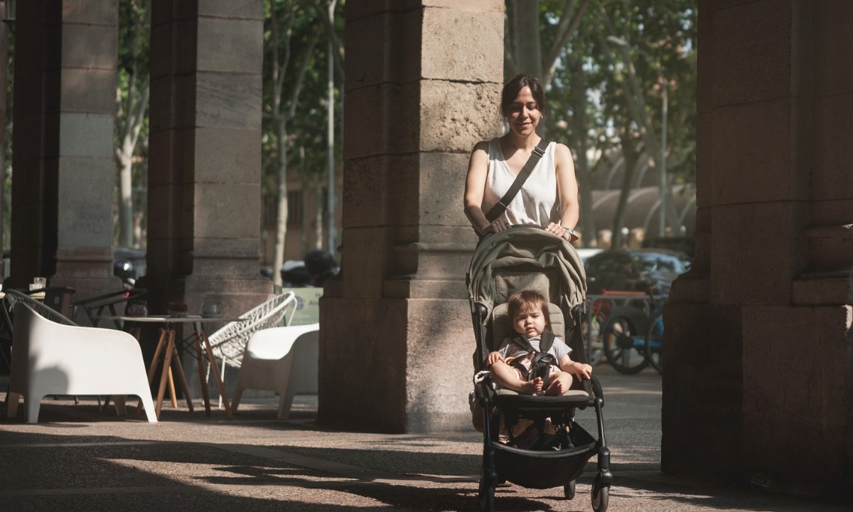A mother pushing a pram along a street