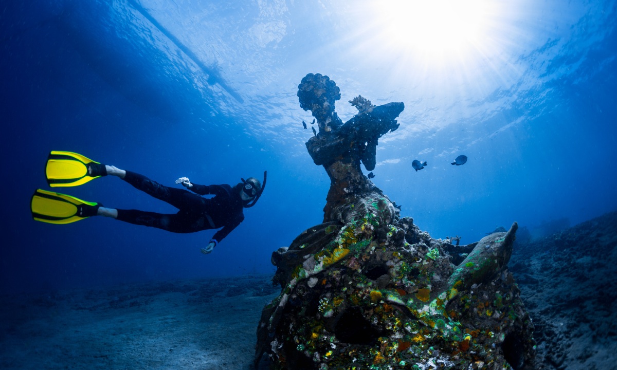 Diver next to underwater sculpture under the sea at MUSA