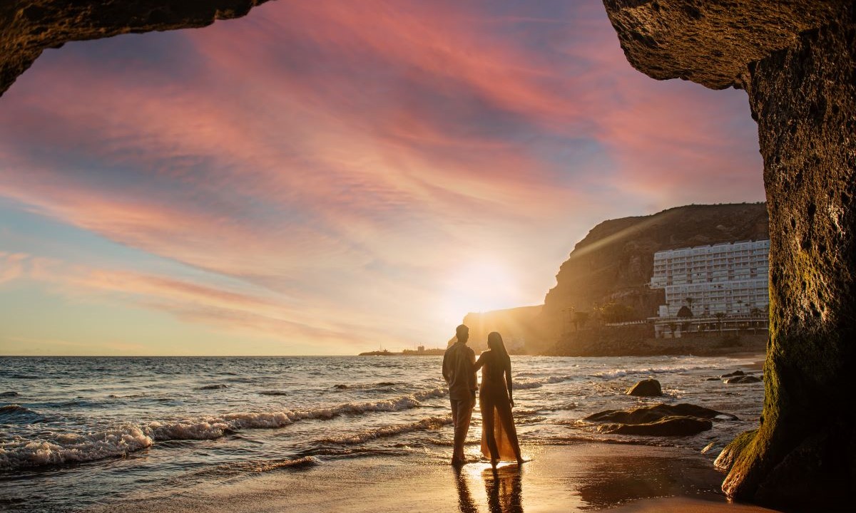 Ein Paar genießt den Sonnenuntergang am Strand von Taurito während eines romantischen Kurzurlaubs im Princess Taurito