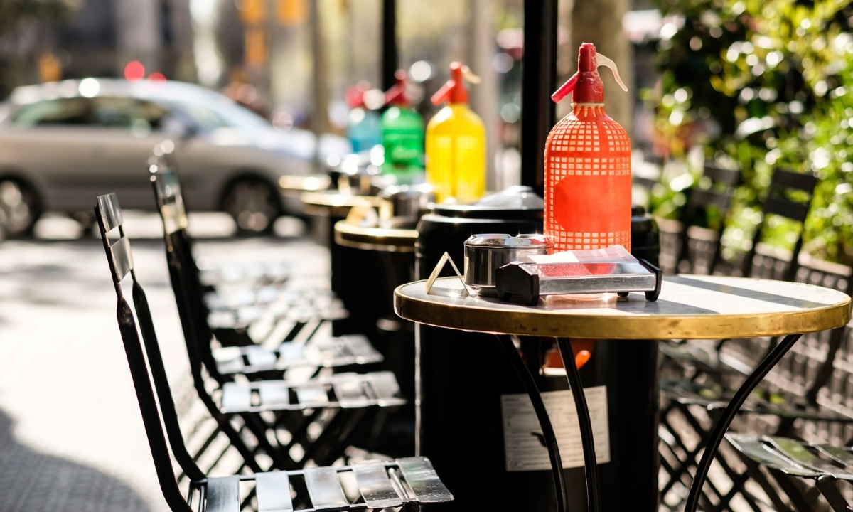 Terrassentische mit farbigen Wermut-Siphons darauf