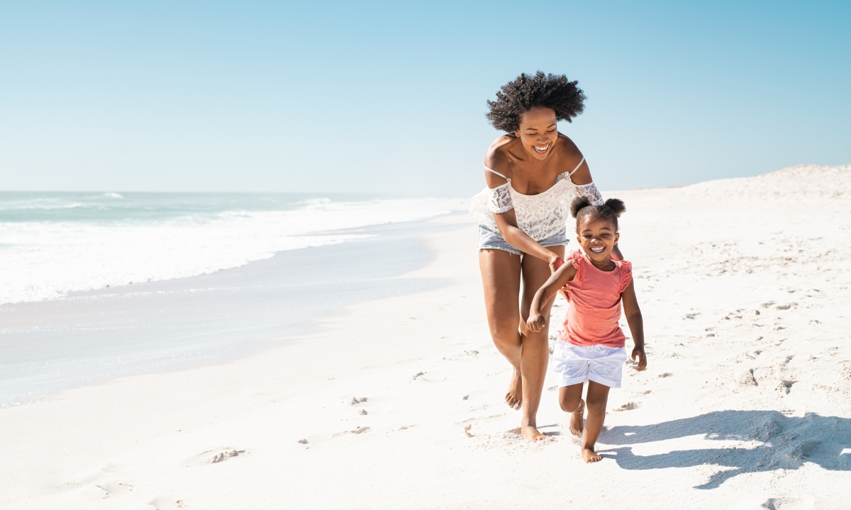 Mother and young daughter strolling along the shore