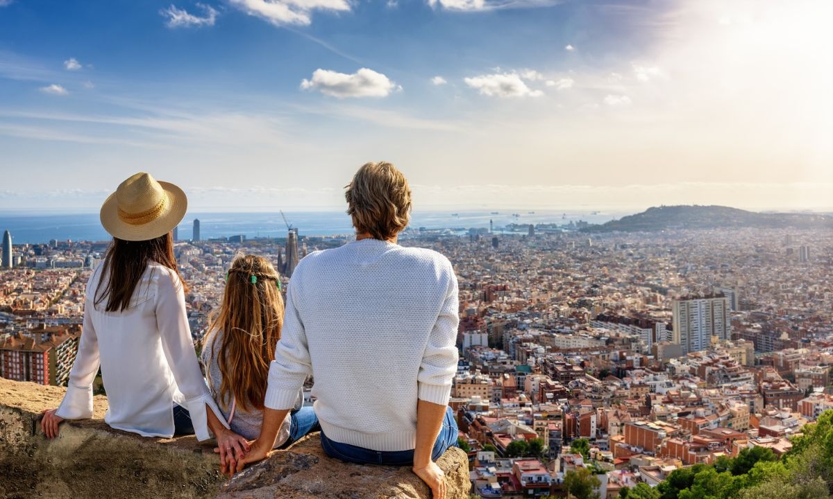 A father, mother and daughter at a viewpoint looking out over Barcelona