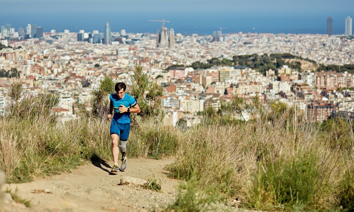 A man running along a path with Barcelona in the background