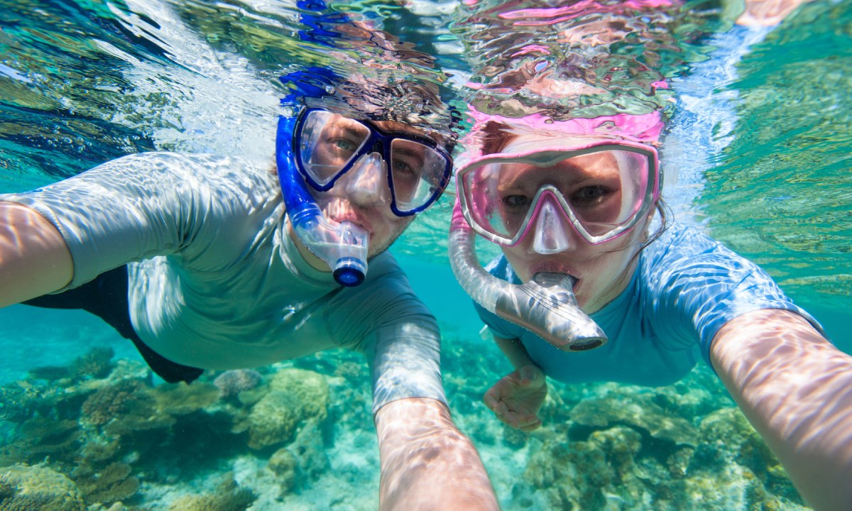 hombre y mujer haciendo selfie bajo el agua con máscaras de buceo