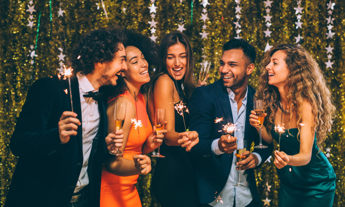 Menschen feiern den Jahreswechsel mit Wunderkerzen und Sekt