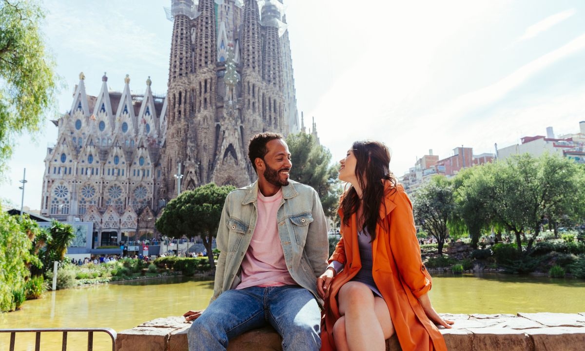 A man and woman sitting in front of the Sagrada Familia