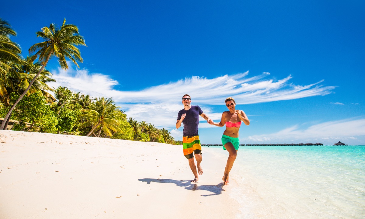 A couple running hand in hand along the seashore