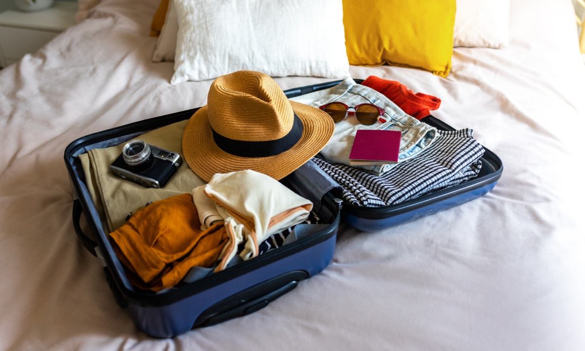 Maleta con sombrero, gafas de sol, cámara y pasaporte