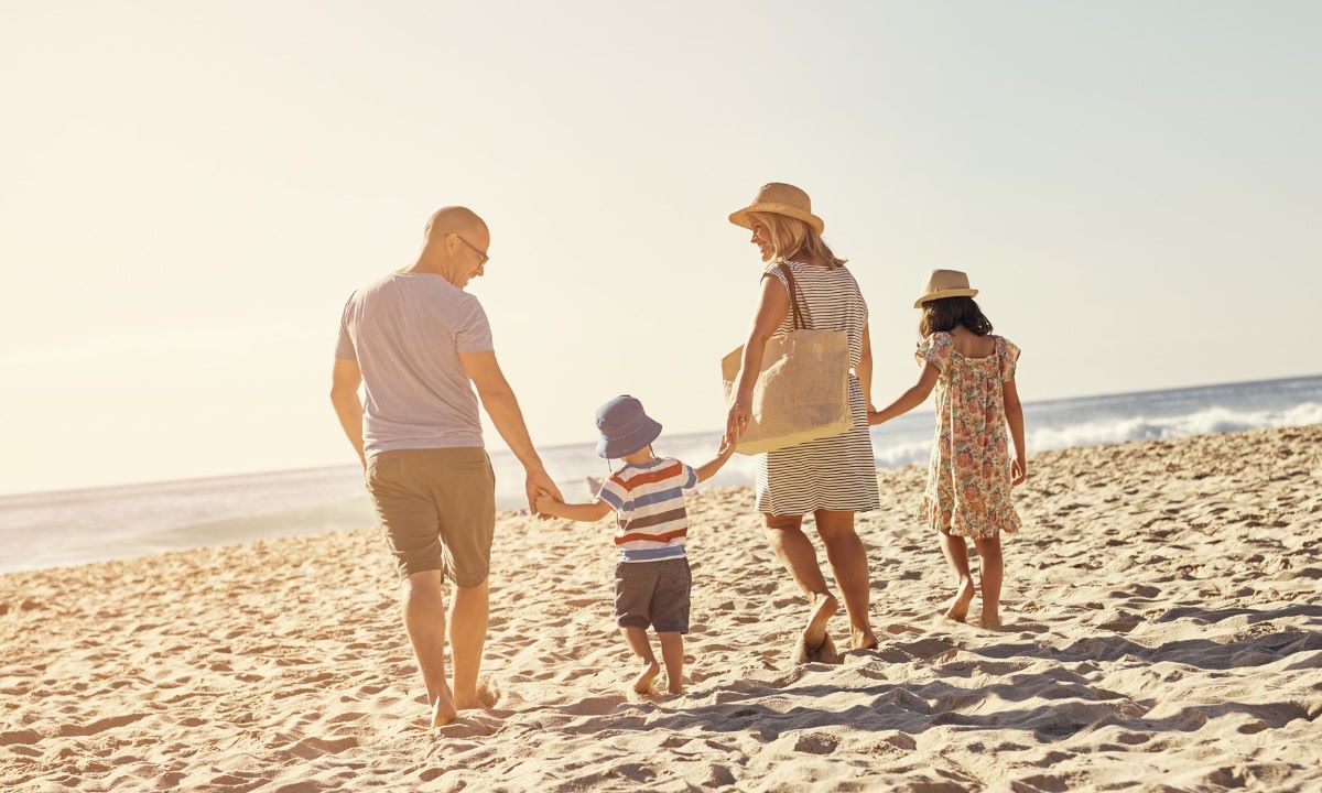 Familia paseando junto en la playa durante sus vacaciones en familia