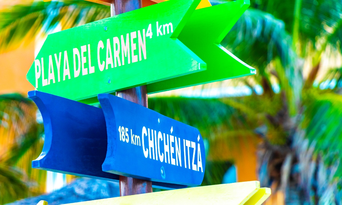 A signpost pointing towards Playa del Carmen and Chichén Itzá