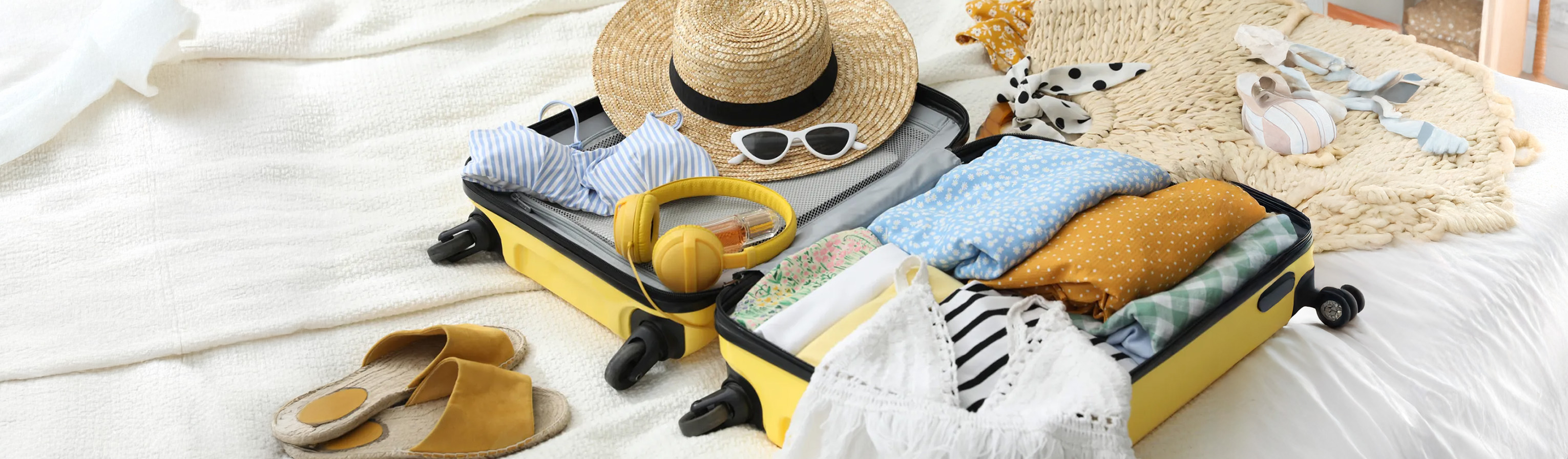 Maleta con artículos de verano sobre cama
