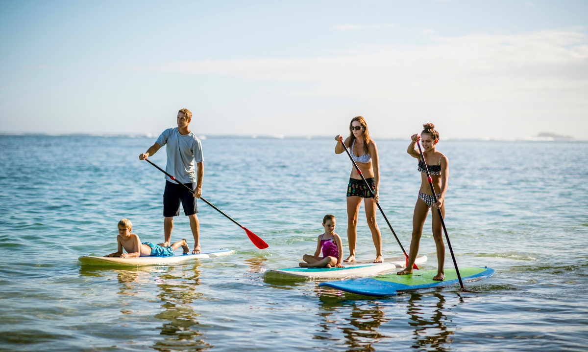 Gruppe von Personen beim Stand-up-Paddling auf ruhigem Wasser