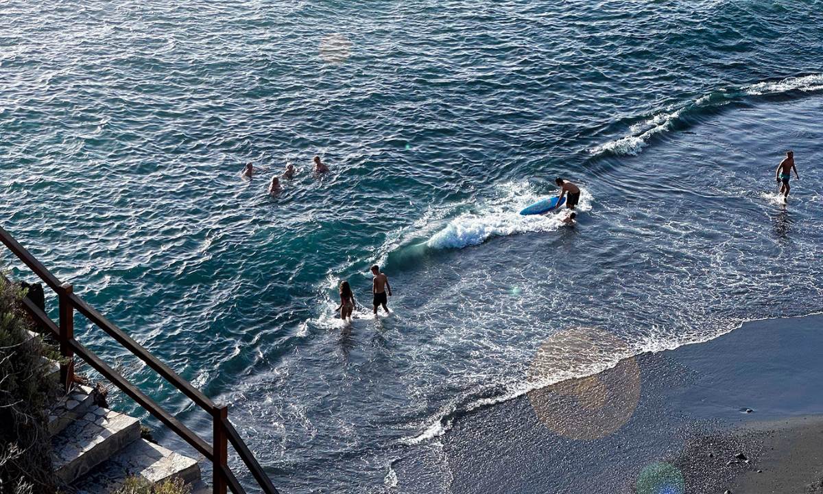Menschen genießen das Meer und surfen an einem schwarzen Sandstrand auf La Palma