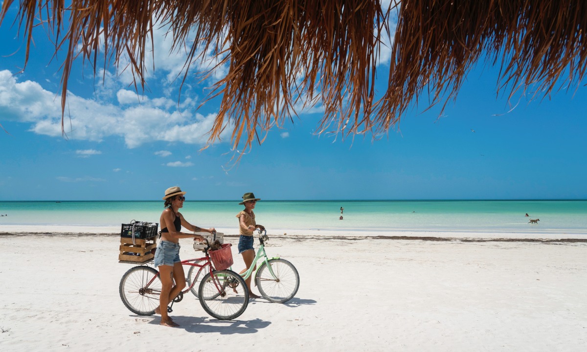 Frauen mit Fahrrädern am Strand von Holbox