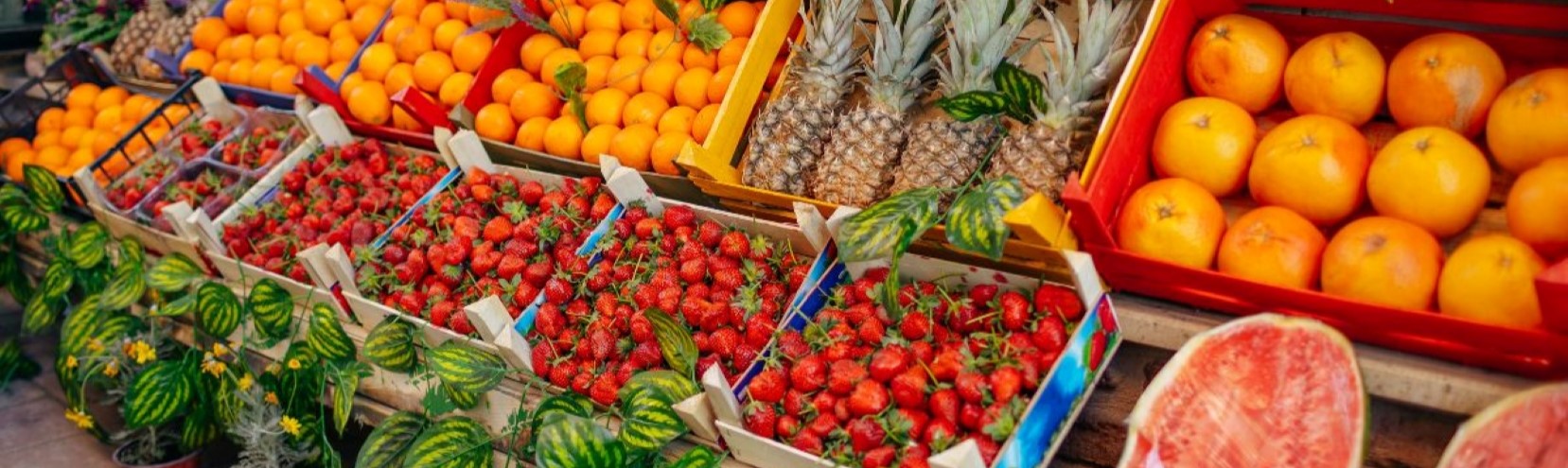 Puesto de mercado con fresas, piñas y naranjas frescas en un mercadillo tradicional de Tenerife.