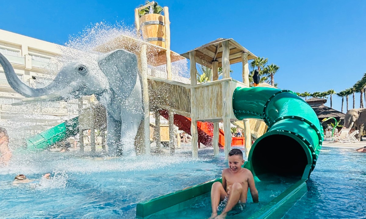 Niño deslizándose por un tobogán verde en el parque acuático infantil Splash Park del hotel Maspalomas & Tabaiba Princess.