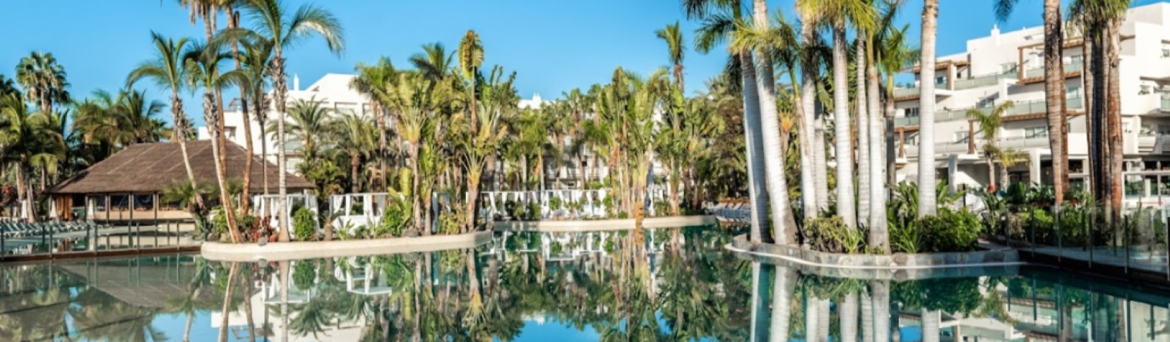 Gran piscina de diseño tropical rodeada de altas palmeras caribeñas en el hotel Maspalomas & Tabaiba Princess en Gran Canaria.