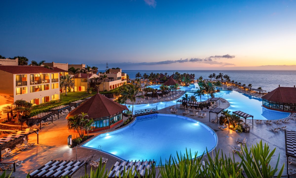Vistas nocturnas de las piscinas iluminadas del hotel La Palma Princess junto al mar durante el atardecer en La Palma.