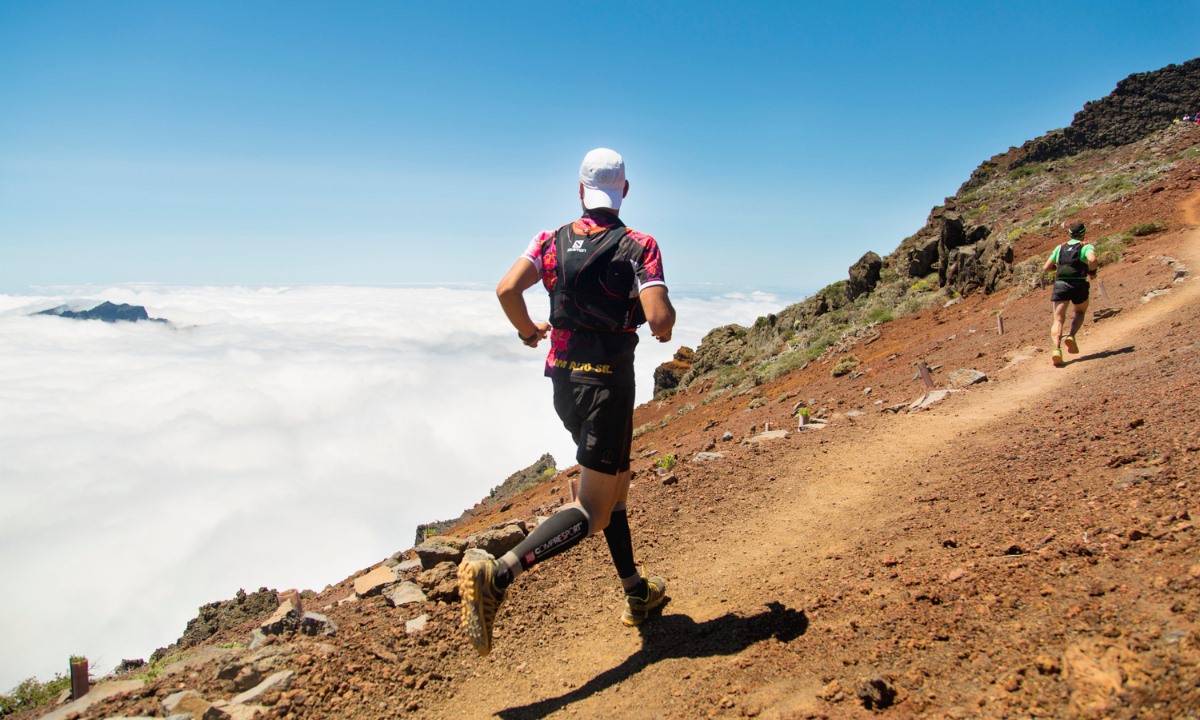 Corredores de la ultramaratón Transvulcania en La Palma compitiendo por un sendero de montaña sobre un mar de nubes.