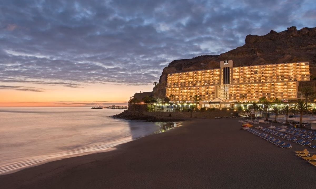 Fachada iluminada al atardecer del hotel todo incluido Taurito Princess a pie de playa en Gran Canaria.