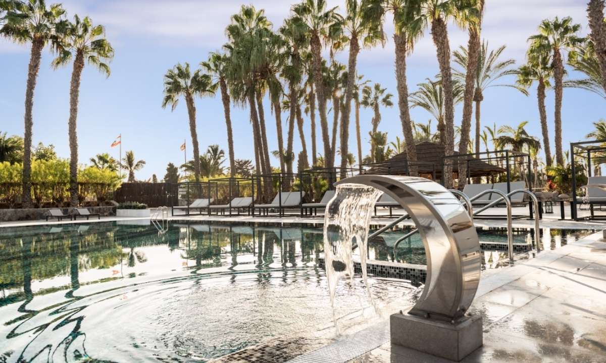 Piscina con cascada de agua y hamacas entre palmeras en la zona solo adultos de Maspalomas & Tabaiba Princess.