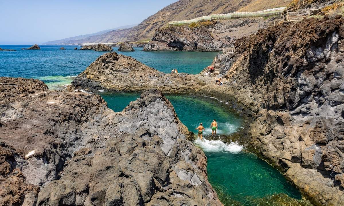 Bañistas disfrutando en una piscina natural entre rocas volcánicas en La Palma