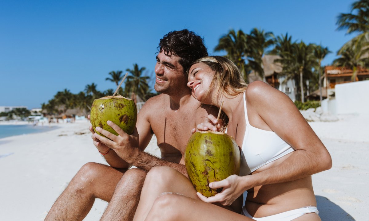  couple drinking coconut water on the shore