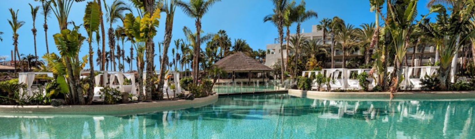 Piscina de aguas cristalinas rodeada de palmeras tropicales en el hotel Maspalomas y Tabaiba Princess