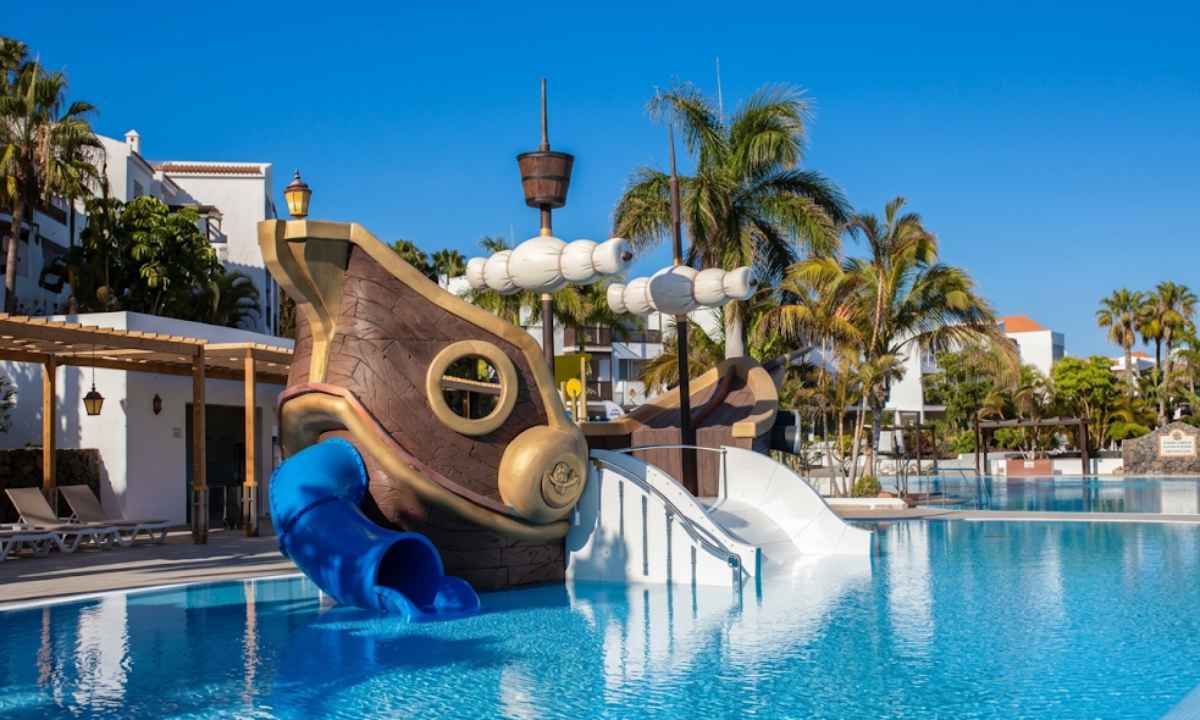 Piscina infantil del hotel Fuerteventura Princess con un barco pirata de madera y tobogán para el entretenimiento familiar.