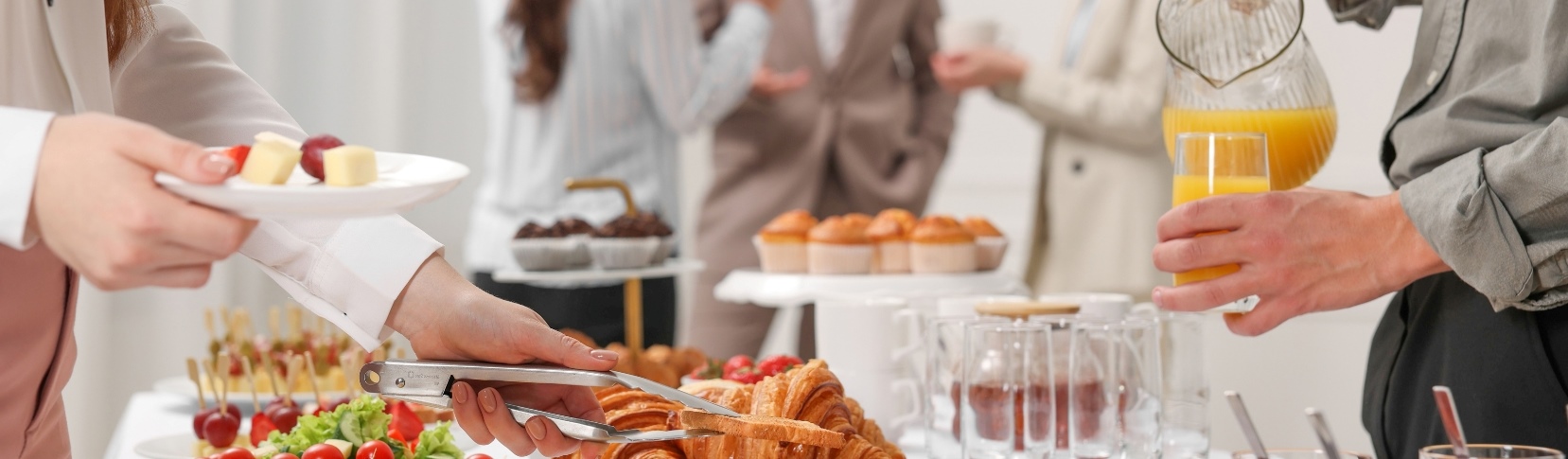 Asistentes a un evento corporativo sirviéndose un desayuno de un bufet.