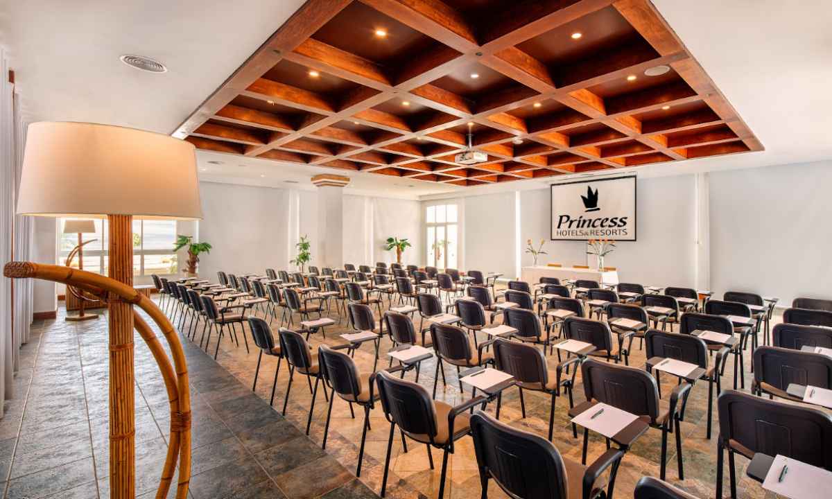 Sala de reuniones con techo artesanal de madera, sillas equipadas con pala de escritura y proyector en el hotel Fuerteventura Princess.