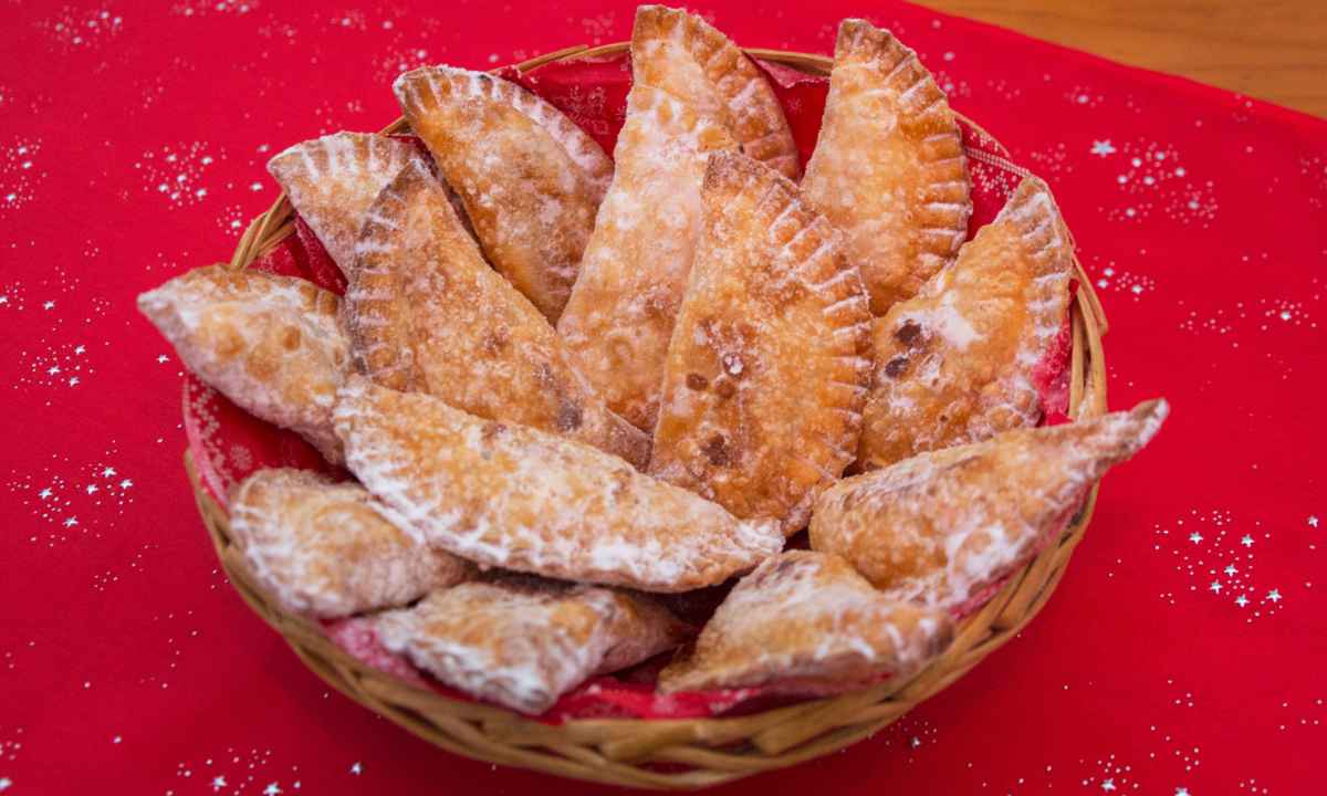 Cesta de mimbre con truchas de batata canarias espolvoreadas con azúcar sobre un mantel rojo navideño.
